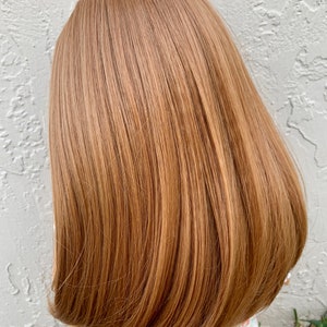 May include: A doll with long, straight, light brown hair. The hair is styled in a simple, sleek bob.