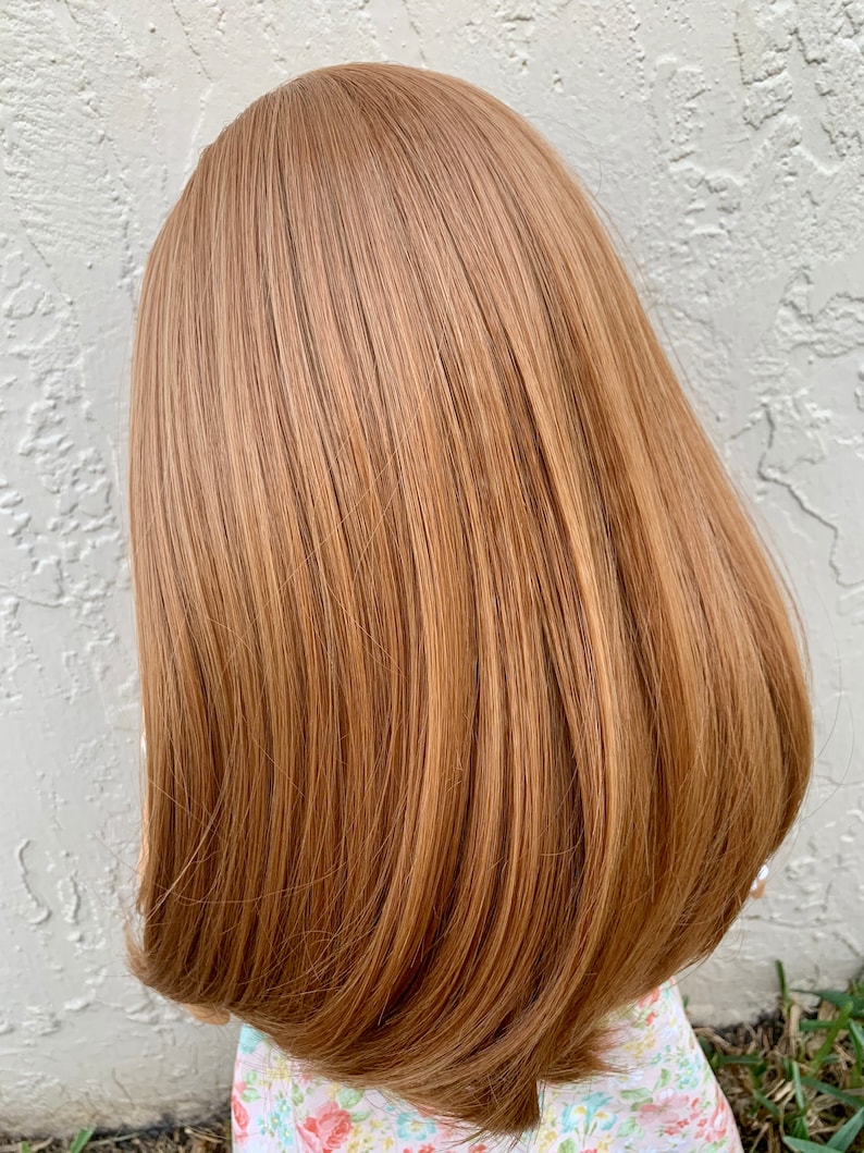 May include: A doll with long, straight, light brown hair. The hair is styled in a simple, sleek bob.