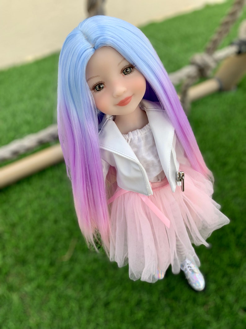 May include: A doll with long, ombre hair that transitions from light blue to purple. She is wearing a white jacket, a pink tulle skirt, and white shoes.