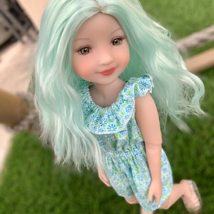 May include: A doll with long, wavy, light green hair wearing a blue and white floral print dress. The doll has brown eyes and a light pink blush.