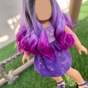 May include: A doll with long, wavy hair that transitions from gray to purple and then to a vibrant magenta. The doll wears a purple dress with gold speckles and matching sandals.