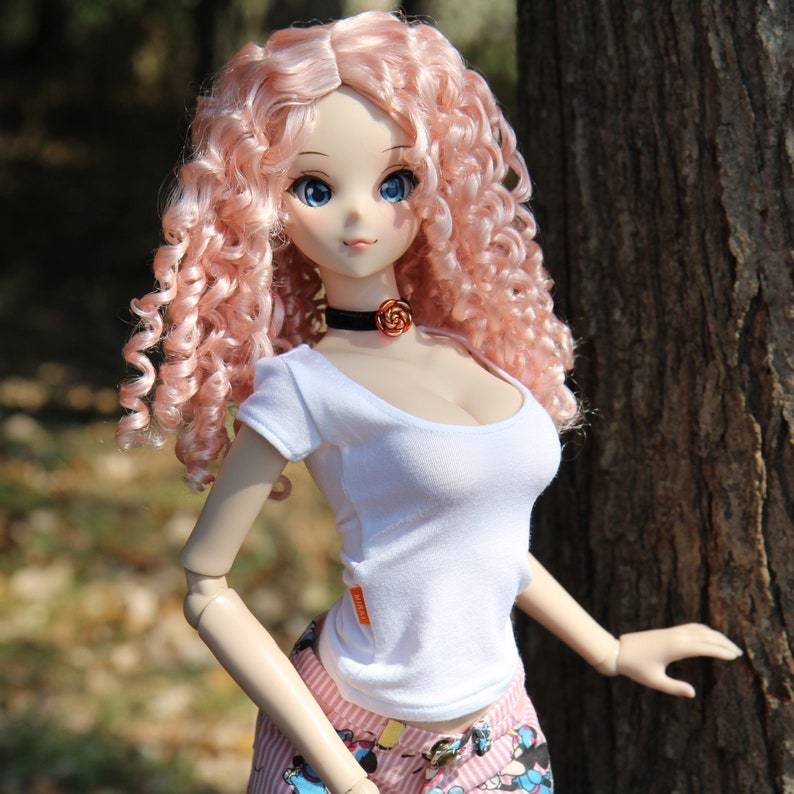 May include: A doll with long pink curly hair wearing a white t-shirt and a pink and white patterned skirt. The doll is wearing a black choker with a rose-shaped pendant.