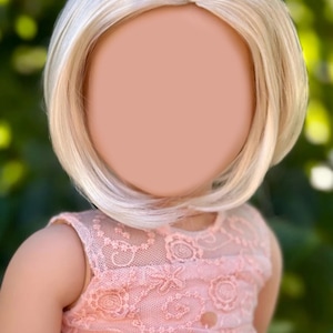 Könnte beinhalten: Eine Puppe mit einer blonden Perücke, die ein rosa Spitzenoberteil trägt.