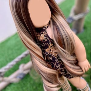 May include: A long, wavy doll wig with brown, blonde, and light brown streaks. The wig is styled in a center part with long layers.