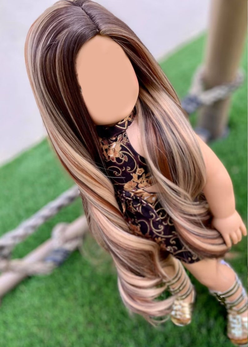 May include: A long, wavy doll wig with brown, blonde, and light brown streaks. The wig is styled in a center part with long layers.