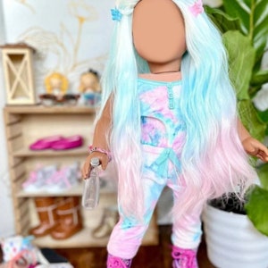 Könnte beinhalten: Eine Puppe, die ein Batik-Outfit in Pink und Blau trägt, Rollschuhe und herzförmige Sonnenbrillen. Die Puppe hat langes, welliges, hellblaues und rosa Haar mit Schmetterlingshaarklammern.