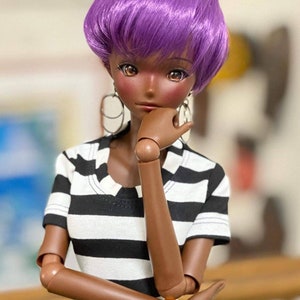 May include: A doll with dark skin, wearing a black and white striped shirt, and a purple wig. The doll has large eyes, hoop earrings, and an orange bracelet. The doll is posed with a hand on its chin, suggesting contemplation.