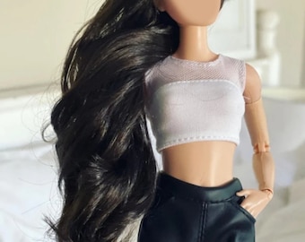 Peut inclure: Une poupée mannequin avec de longs cheveux brun foncé et un haut court blanc. La poupée porte un short noir et a une main dans une poche. Le visage de la poupée est vierge. L'arrière-plan est de couleur neutre.