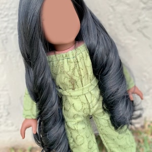 May include: A doll with long black hair wearing a green jumpsuit with a key necklace.