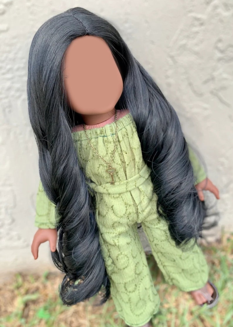 May include: A doll with long black hair wearing a green jumpsuit with a key necklace.