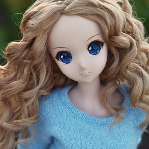 May include: A doll with long, curly blonde hair wearing a light blue sweater.