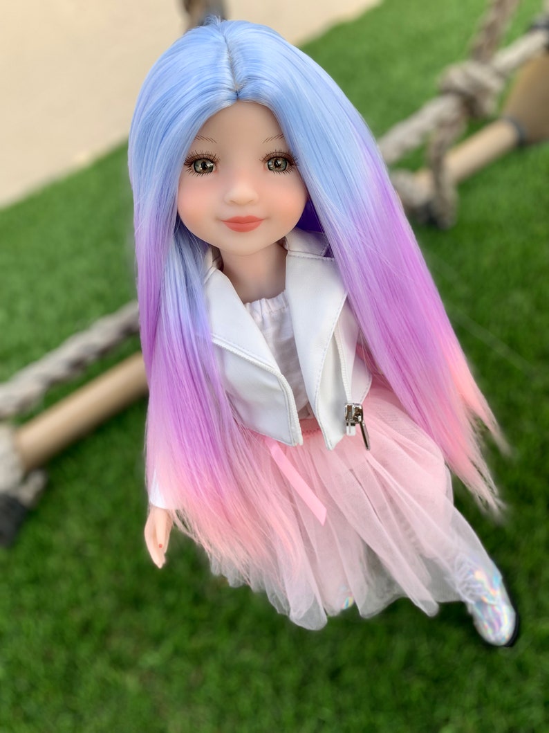 May include: A doll with long, ombre hair that transitions from light blue to purple to pink. She is wearing a white jacket and a pink tulle skirt.