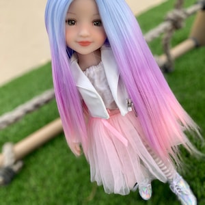 May include: A doll with long, ombre hair that transitions from light blue to pink. The doll is wearing a white jacket, a pink tulle skirt, and white and black striped tights.