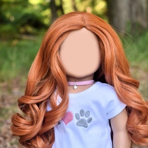 May include: A doll with long, curly, auburn hair wearing a white t-shirt with a pink heart and gray paw print design. The doll is also wearing a gray and orange skirt with paw prints and hearts. The doll is wearing a pink choker with a silver heart charm and a pink beaded bracelet.