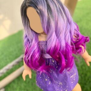 May include: A doll with long, wavy hair in a gradient of colors, starting with black at the roots, transitioning to lavender, and ending in vibrant magenta. The doll wears a purple dress with gold speckles and sandals.