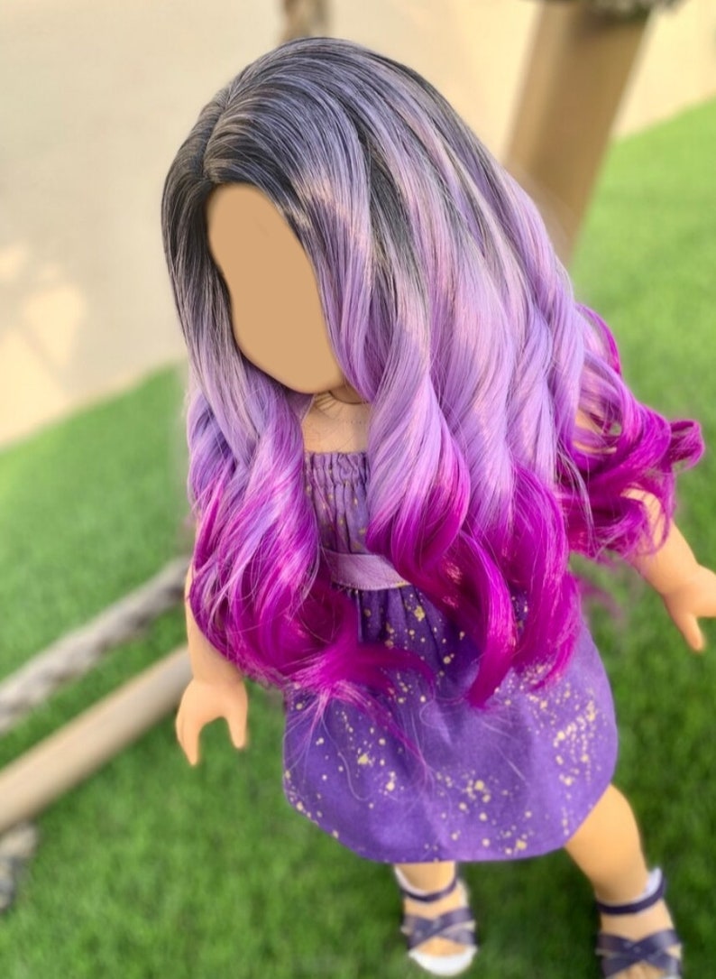 May include: A doll with long, wavy hair in a gradient of colors, starting with black at the roots, transitioning to lavender, and ending in vibrant magenta. The doll wears a purple dress with gold speckles and sandals.