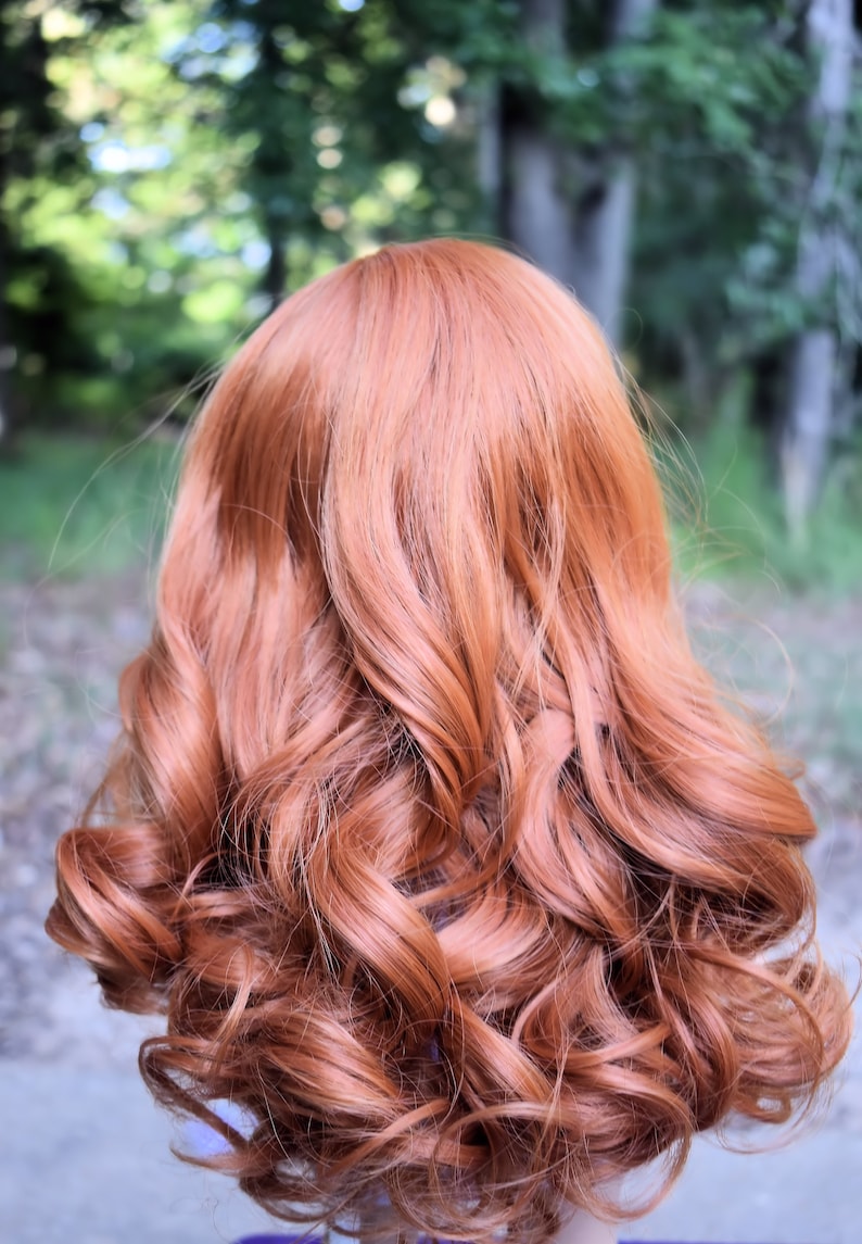 May include: A long, curly, auburn-colored wig. The wig is styled in loose curls and falls to the shoulders.