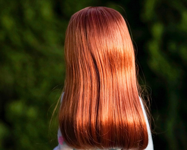 May include: A doll with long, straight, auburn hair. The hair is styled in a simple, sleek look.