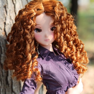 May include: A doll with long, curly, auburn hair wearing a purple shirt with a ruffled collar.