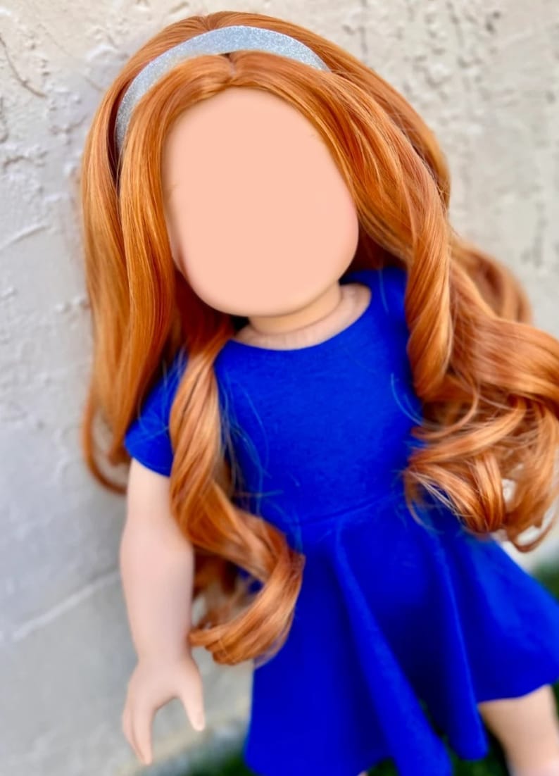 May include: A doll with long, curly, auburn hair wearing a blue dress and a silver headband.