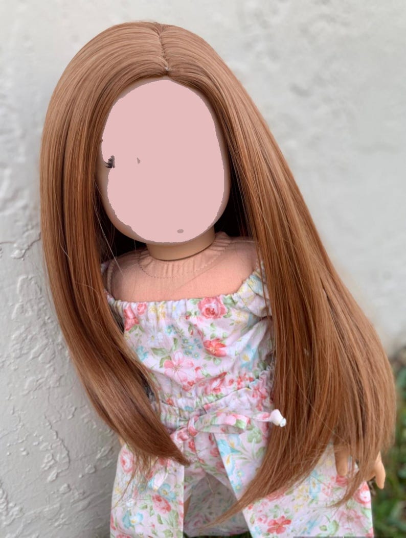 May include: A long, straight, auburn-colored wig for a doll. The wig is styled with a center part and falls to the doll's shoulders.
