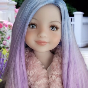 May include: A doll with long, straight, ombre hair that transitions from light blue to lavender. The doll is wearing a pink fuzzy jacket.