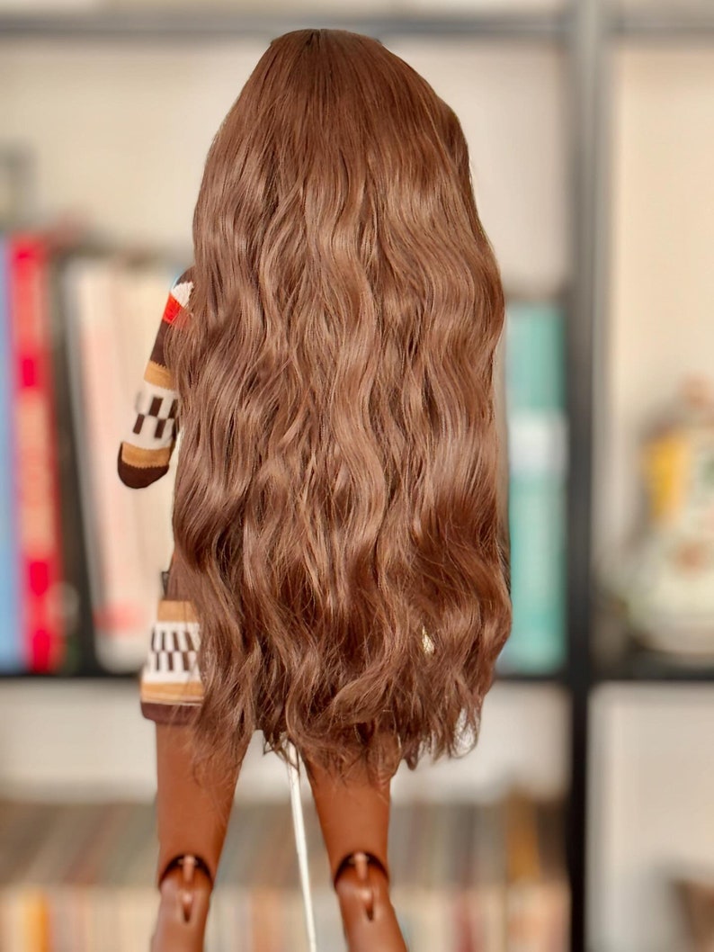 May include: A long, wavy brown wig with a natural-looking texture. The wig is styled in a loose, flowing style, with the ends of the hair falling just below the shoulders.