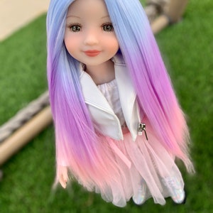 May include: A doll with long, ombre hair that transitions from light blue to purple to pink. The doll is wearing a white jacket, a pink tulle skirt, and sparkly shoes.