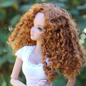 May include: A doll with long, curly, auburn hair wearing a white lace-trimmed top.