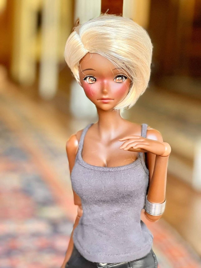 May include: A doll with dark skin and blonde hair wearing a gray tank top and black pants.