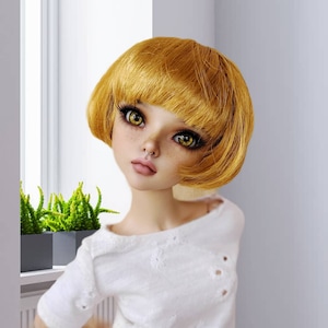 May include: A doll with short, bright yellow hair, wearing a white shirt. The doll has yellow eyes and a nose ring.