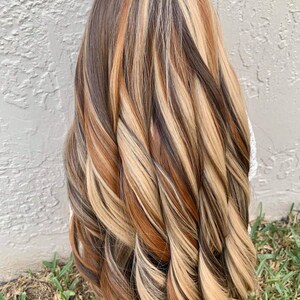 May include: Long, wavy hair with highlights in shades of brown, blonde, and copper.