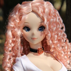 May include: A doll with long, curly, pink hair. The doll is wearing a white shirt and a black choker with a red rose charm.