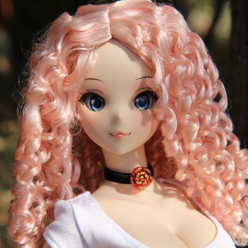 May include: A doll with long, curly, pink hair. The doll is wearing a white shirt and a black choker with a red rose charm.
