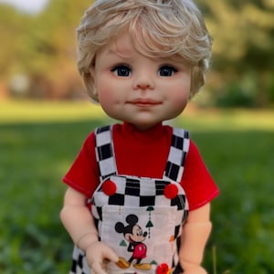 May include: A doll with blonde hair wearing a red shirt and black and white checkered overalls with a Mickey Mouse design.
