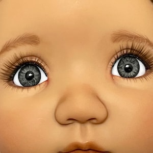May include: Close-up of a doll's face with gray eyes and brown eyebrows.
