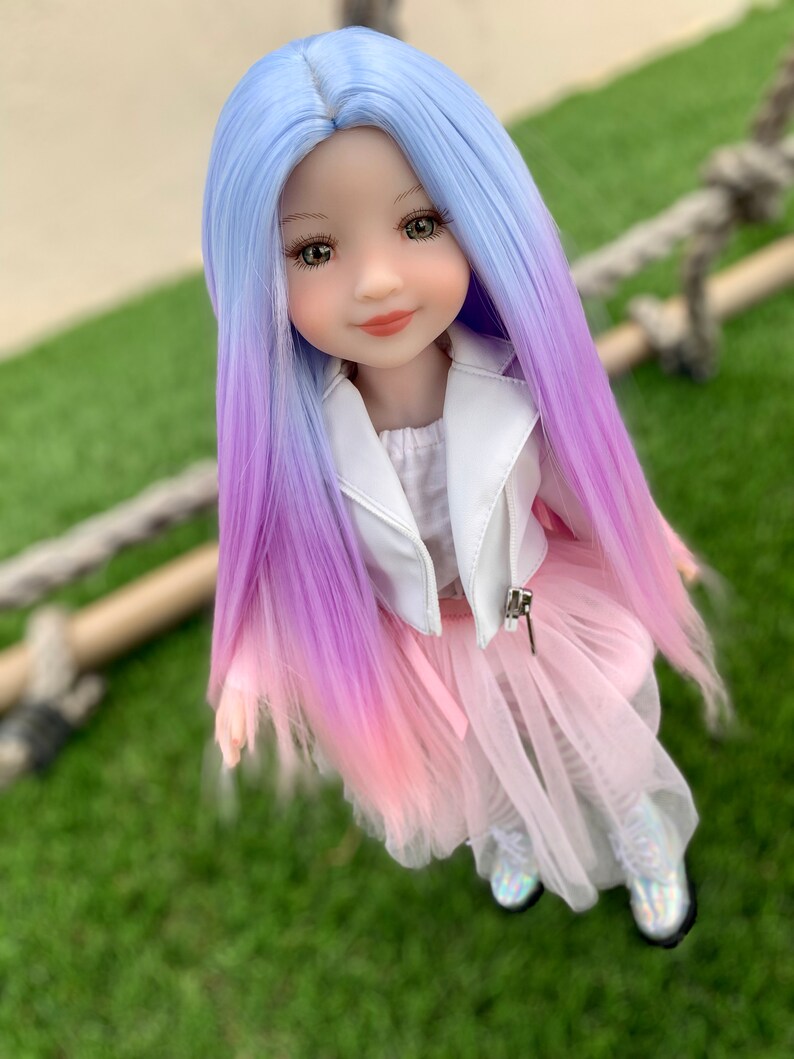 May include: A doll with long, ombre hair that transitions from light blue to purple to pink. She is wearing a white leather jacket, a pink tulle skirt, and white boots.