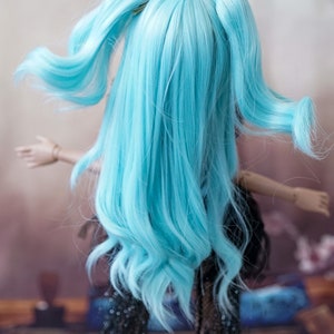 Puede incluir: Una mu&ntilde;eca con el pelo largo y azul brillante peinado en dos coletas altas. El pelo es ondulado y fluido. La mu&ntilde;eca lleva un vestido negro con lentejuelas.