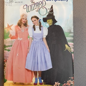 May include: Simplicity sewing pattern number 4136 for The Wizard of Oz costumes. The pattern includes three costumes: a pink dress with a star, a blue gingham dress with a white pinafore, and a black and green witch costume. The pattern is for sizes 6, 8, 10, and 12.