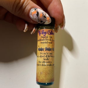 May include: A small glass bottle with a green liquid inside. The bottle has a label that says "The Sage's Cauldron Magickal Oils blended for all of your magickal needs Mister Sister Oil For use by men... to attract all the boys you handle! Use with caution... to use to dress candles, put"