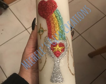 Può includere: Candela bianca con un design a forma di arcobaleno, cuore e calice. Il design è realizzato con glitter e presenta un cuore rosso con una stella dorata al centro.
