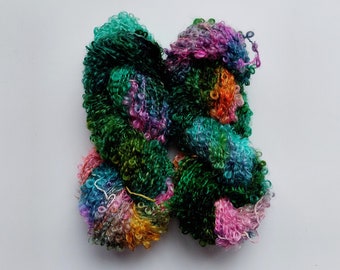 May include: A skein of colourful yarn with a fuzzy texture. The yarn is a mix of green, pink, blue, and orange.