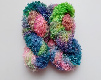 May include: A skein of colourful yarn with a fuzzy texture. The yarn is a mix of pink, green, blue, and purple.
