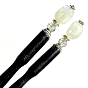 May include: Two black wooden hair sticks with iridescent white gemstone and crystal accents.