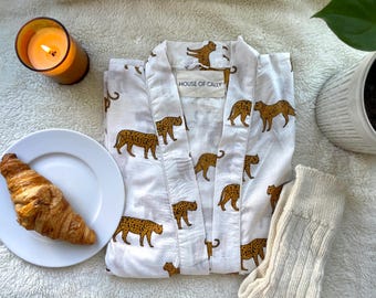 May include: White robe with a leopard print pattern. The robe has a tie closure and a label that reads "House of Cally".