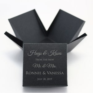 May include: Black gift box with a white inscription that reads "Hugs & Kisses From the New Mr. & Mrs. Ronnie & Vanessa July 20, 2019".
