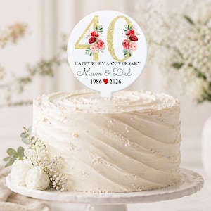May include: A white iced cake with a topper celebrating a 40th Ruby Anniversary. The topper features gold glitter numbers, floral designs, and the text "Happy Ruby Anniversary Mum & Dad 1986 ❤️ 2026".