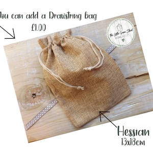 May include: A brown drawstring bag made of hessian fabric. The bag is 13 inches by 18 inches and is sitting on a wooden surface. The text "You can add a Drawstring bag &pound;1.00" is visible above the bag.