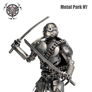 May include: A metal sculpture of a warrior figure holding two swords. The sculpture is made of various metal pieces and has a silver finish. The text "Metal Park NY" is displayed in the upper right corner.
