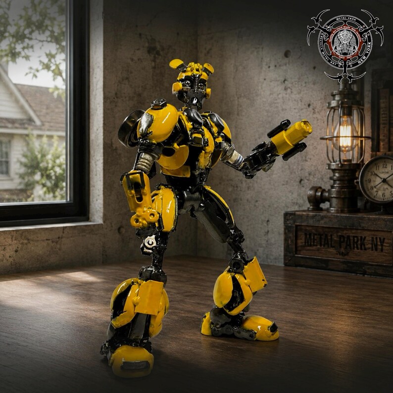 May include: A yellow and black robot figurine constructed from metal parts. The robot features a rounded head with antennae, a segmented torso, and articulated limbs. One arm is extended, holding a cylindrical weapon component. The design incorporates automotive-inspired plating and mechanical joints throughout the structure.